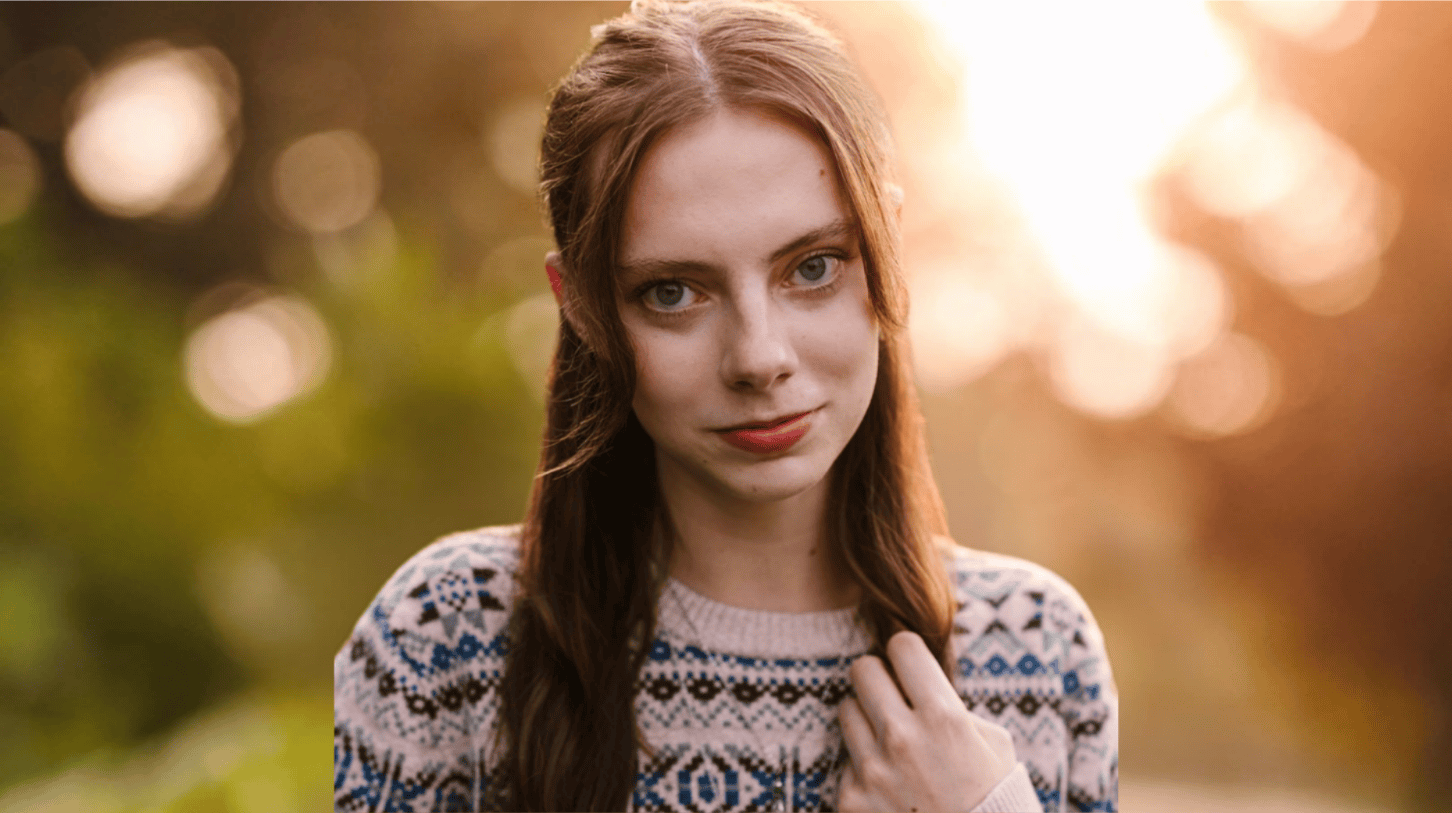 Portrait of a young woman with long hair outdoors in soft, warm light
